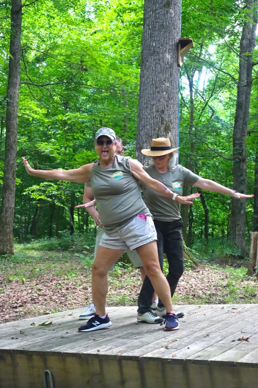 Two guests in matching shirts on a wooden platform with their arms out like they're flying