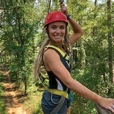 Happy female smiling and wearing zipline equipment, ready to start her zipline ride