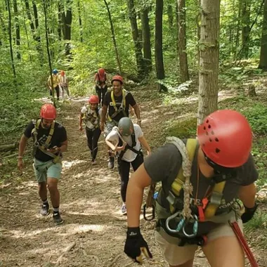 Group of people walking up a trail toward the top platform of a zipline course